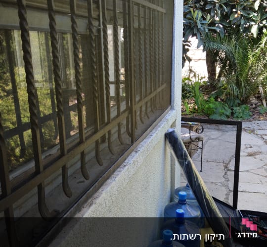 חלון עם סורגים וכלים לידו בחוץ